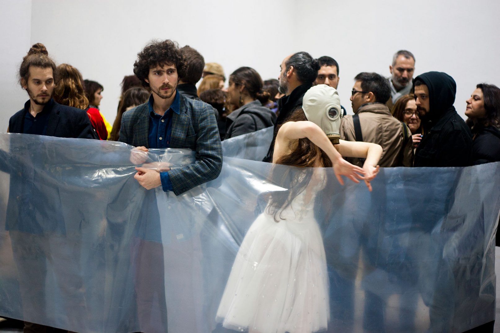 from the work breathe. performers roll the audience with cellophane. Ballerina with full face mask dances