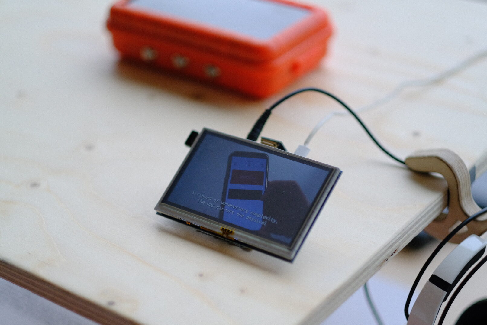 a detail of a small raspberry pi screen. On the background the device called crossborder toolkit, an orange device with solar panel